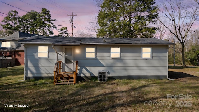 rear view of property with central AC and a lawn