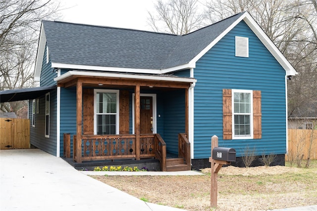 view of front of house featuring driveway, fence, covered porch, roof with shingles, and a carport