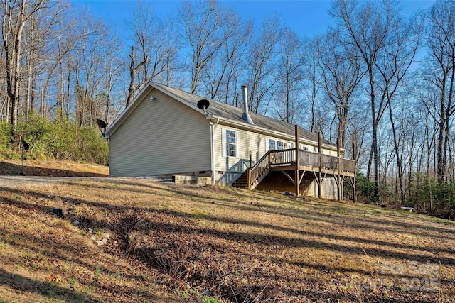 view of home's exterior with a deck, stairway, a yard, and crawl space