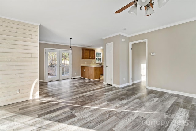 unfurnished living room with a ceiling fan, wood finished floors, baseboards, ornamental molding, and french doors