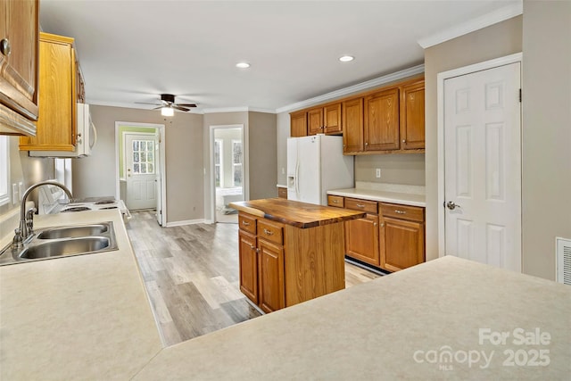 kitchen with light wood finished floors, crown molding, ceiling fan, white fridge with ice dispenser, and a sink