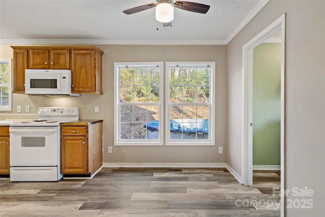 kitchen with white appliances, plenty of natural light, brown cabinets, and crown molding