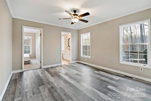 unfurnished bedroom featuring wood finished floors, visible vents, baseboards, ensuite bathroom, and crown molding