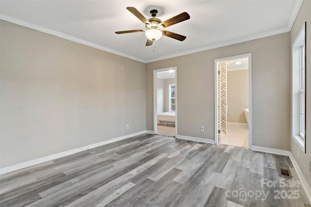 unfurnished bedroom with wood finished floors, visible vents, baseboards, ornamental molding, and ensuite bathroom