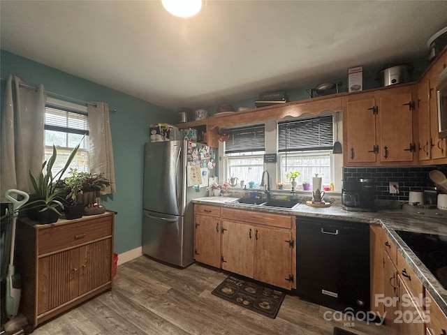 kitchen with light wood-style flooring, freestanding refrigerator, a sink, decorative backsplash, and dishwasher