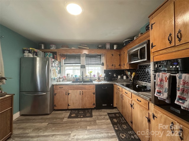 kitchen with light wood-type flooring, black appliances, a sink, backsplash, and brown cabinetry