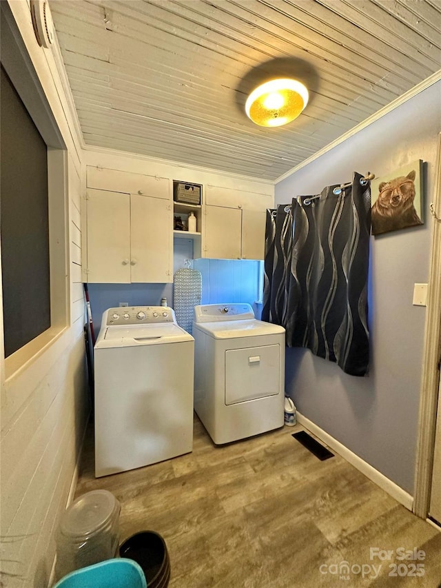 laundry area featuring wood finished floors, cabinet space, separate washer and dryer, crown molding, and wooden ceiling