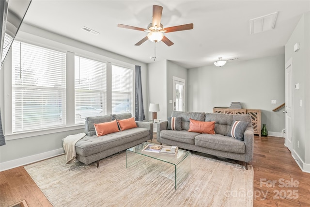 living room with baseboards, visible vents, and wood finished floors