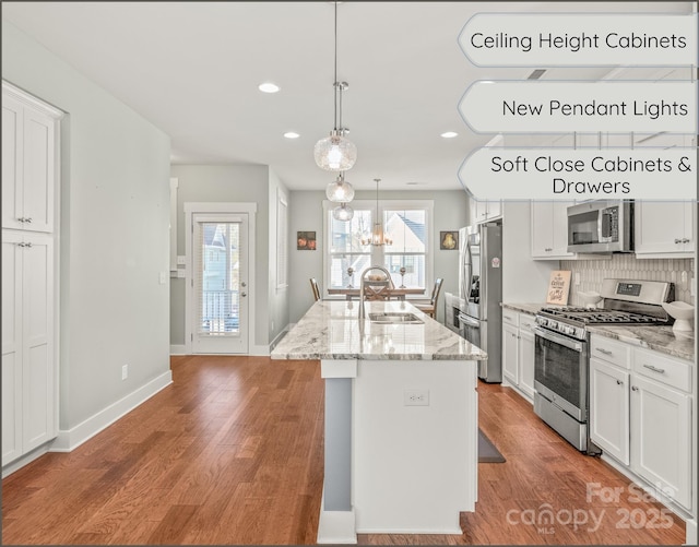 kitchen with white cabinets, stainless steel appliances, a sink, and wood finished floors