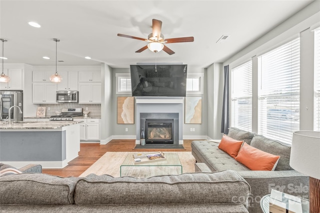 living room with light wood-type flooring, a fireplace, a wealth of natural light, and recessed lighting