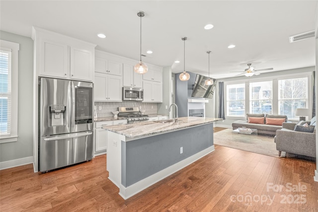 kitchen with appliances with stainless steel finishes, wood finished floors, visible vents, and white cabinetry