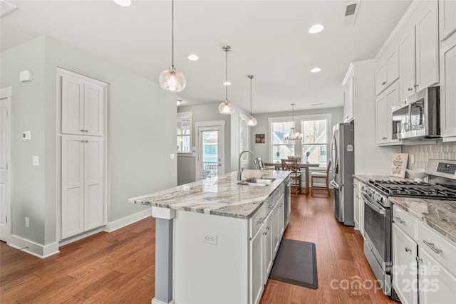 kitchen with white cabinetry, a center island with sink, appliances with stainless steel finishes, and a sink