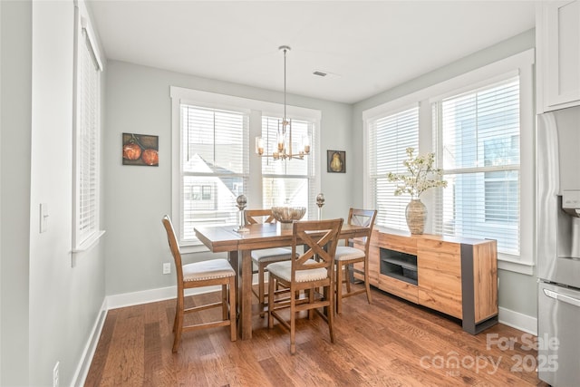 dining space featuring light wood-style floors, baseboards, visible vents, and a notable chandelier