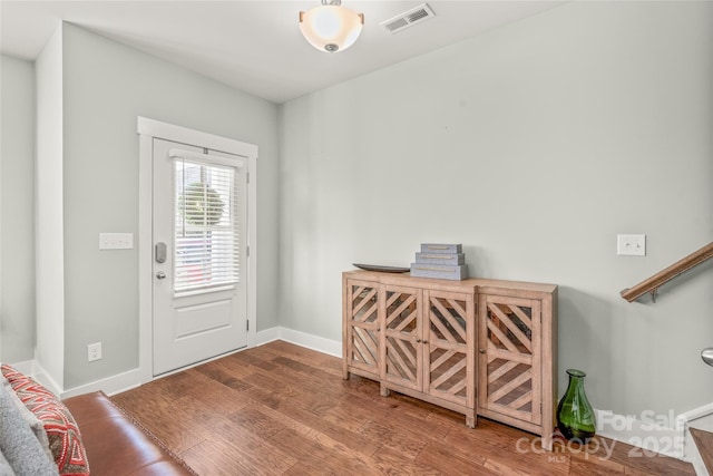 foyer entrance featuring visible vents, baseboards, and wood finished floors