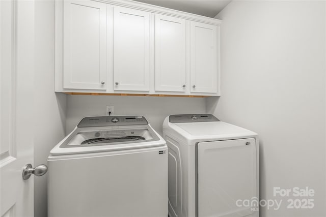 clothes washing area featuring cabinet space and washer and clothes dryer