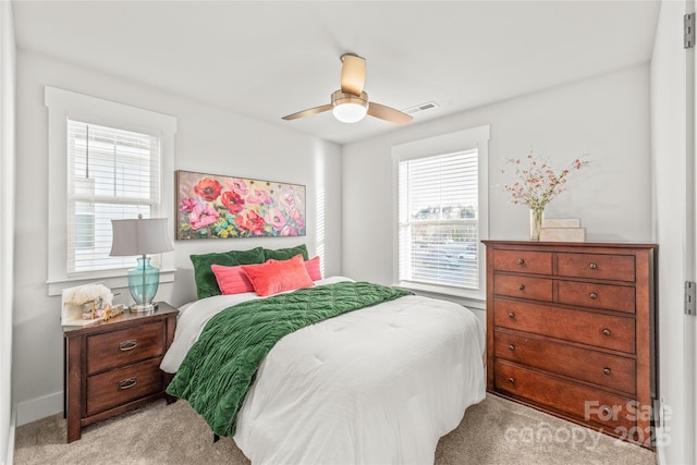 bedroom featuring ceiling fan, visible vents, and light colored carpet