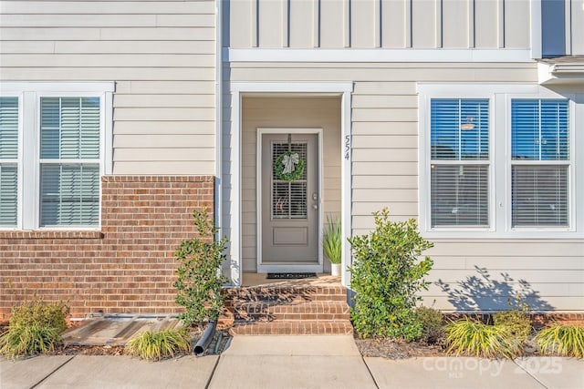 entrance to property featuring board and batten siding and brick siding