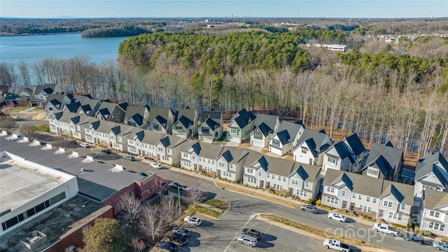 drone / aerial view with a residential view, a water view, and a view of trees