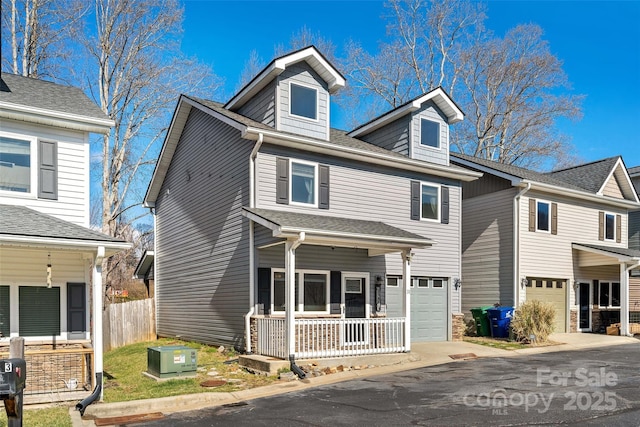 traditional style home with a porch, concrete driveway, a shingled roof, and an attached garage