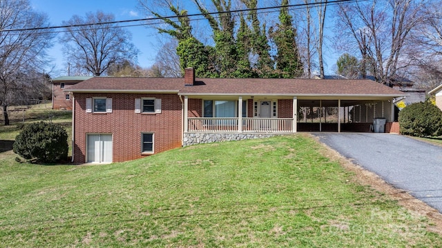 single story home with driveway, brick siding, a chimney, and a front yard