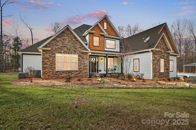 view of front of property featuring stone siding, covered porch, and a lawn