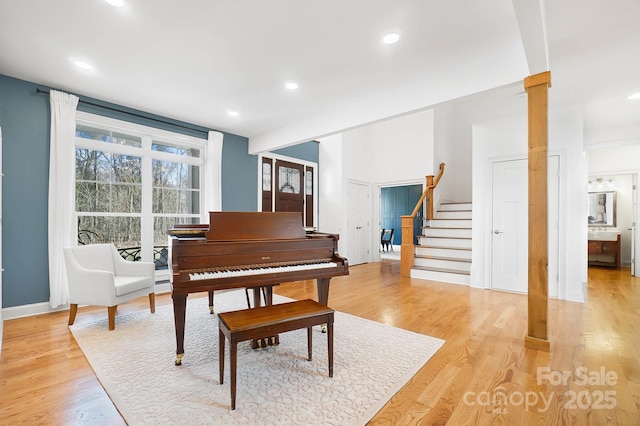 living area featuring light wood-type flooring, decorative columns, recessed lighting, and stairs