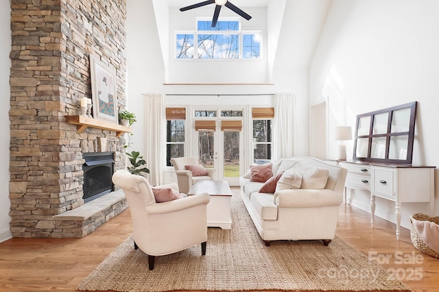 interior space with a wealth of natural light, wood finished floors, and a stone fireplace