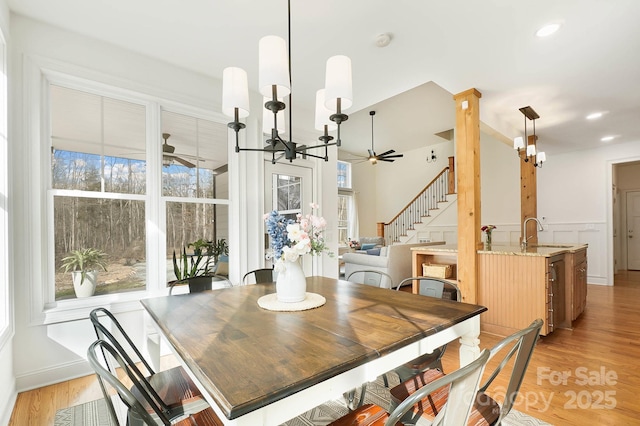 dining room with ceiling fan with notable chandelier, plenty of natural light, and light wood-style floors