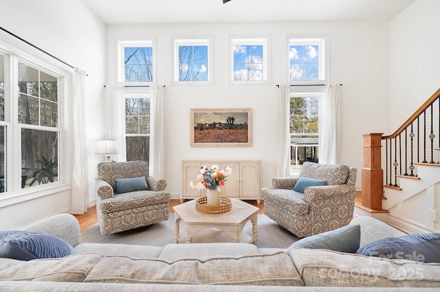 living area featuring a high ceiling, stairway, a wealth of natural light, and wood finished floors