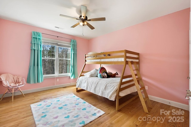 bedroom with a ceiling fan, light wood-type flooring, visible vents, and baseboards