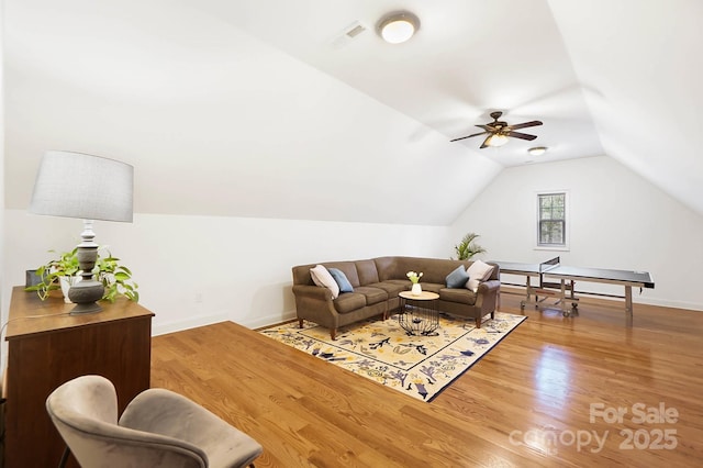 living area featuring visible vents, vaulted ceiling, baseboards, and wood finished floors