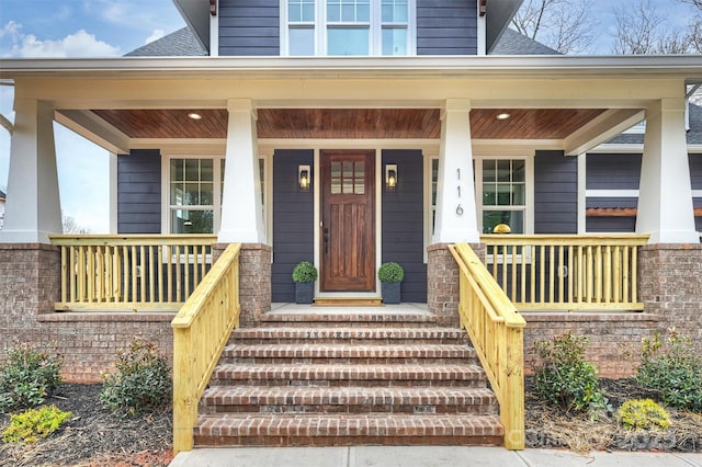 doorway to property with roof with shingles and covered porch