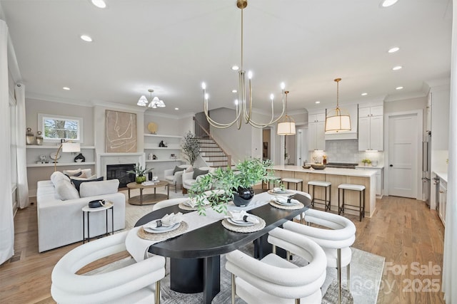 dining room with stairway, light wood finished floors, recessed lighting, a high end fireplace, and crown molding