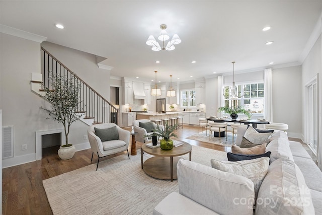 living room with baseboards, an inviting chandelier, stairs, crown molding, and light wood-type flooring