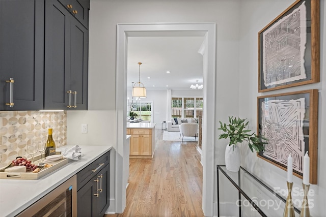 kitchen with decorative backsplash, light countertops, light wood-style flooring, and wine cooler