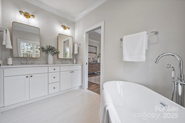 full bath with a sink, a soaking tub, double vanity, and crown molding