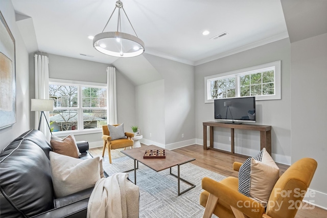 living area featuring visible vents, baseboards, wood finished floors, and ornamental molding