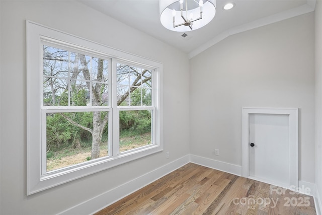 unfurnished room featuring visible vents, baseboards, vaulted ceiling, light wood-type flooring, and a chandelier