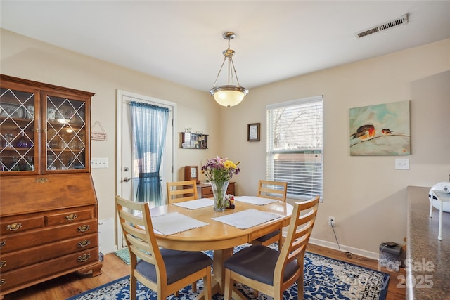 dining room featuring baseboards, visible vents, and light wood finished floors