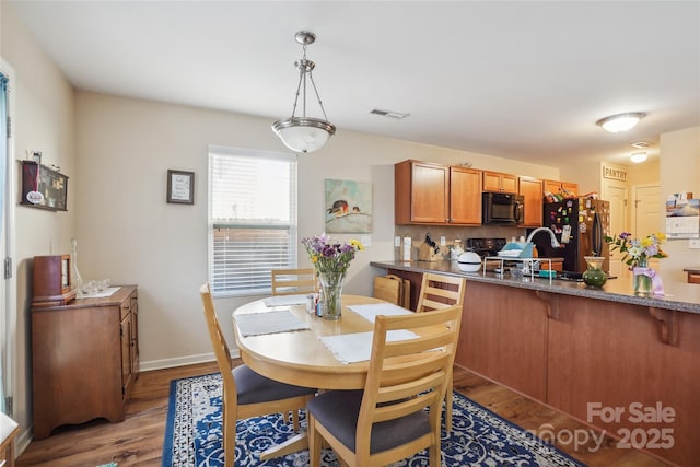 dining room with baseboards, visible vents, and wood finished floors