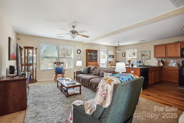 living room featuring a ceiling fan, visible vents, plenty of natural light, and wood finished floors