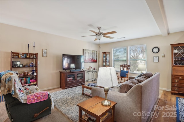 living area with beam ceiling, visible vents, ceiling fan, and baseboards