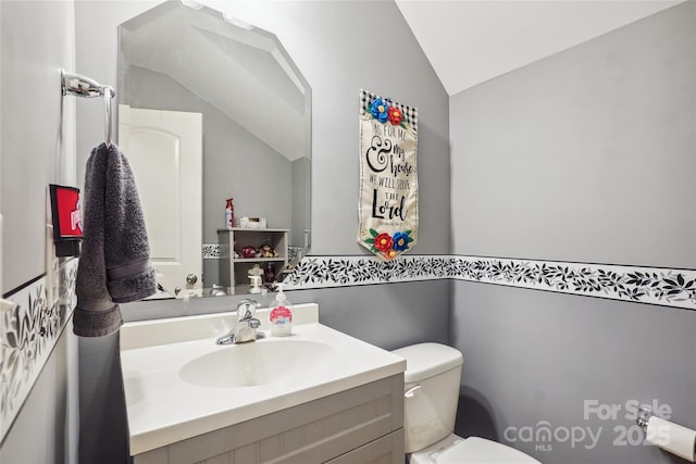 half bathroom with vaulted ceiling, vanity, and toilet