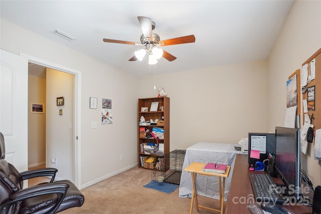 office space with a ceiling fan, light colored carpet, visible vents, and baseboards