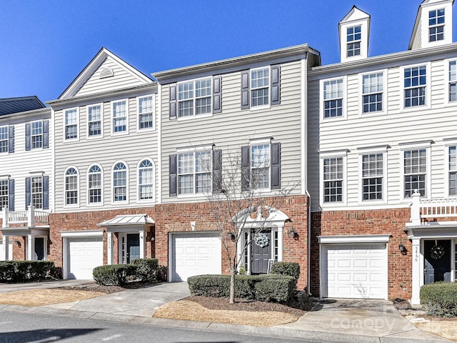 townhome / multi-family property featuring a garage, concrete driveway, and brick siding