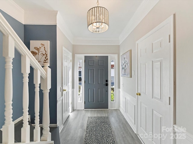 entrance foyer with an inviting chandelier, stairway, wood finished floors, and ornamental molding