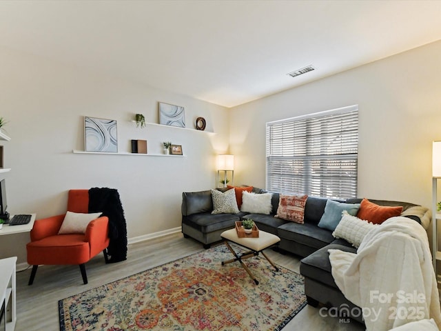 living area with baseboards, visible vents, and wood finished floors