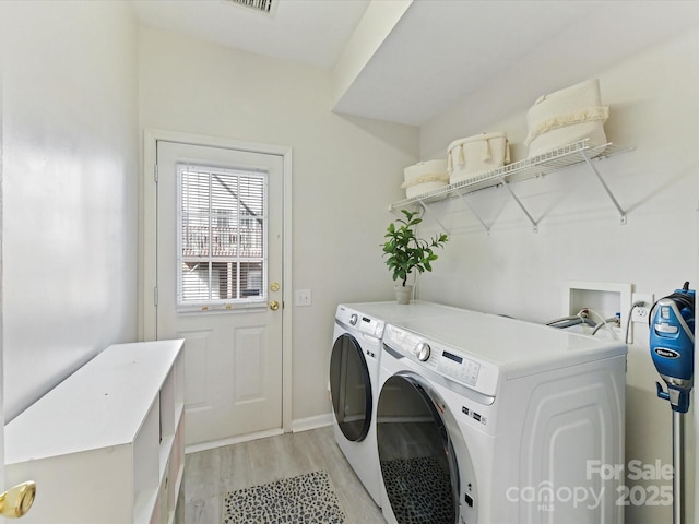 washroom featuring laundry area, washing machine and clothes dryer, and light wood-style flooring