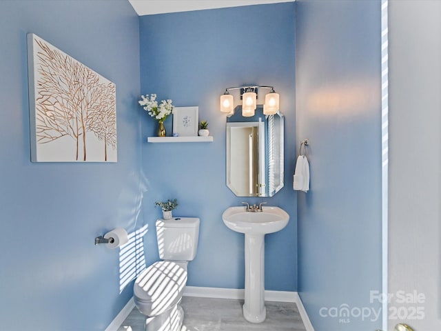 bathroom with toilet, baseboards, and wood finished floors