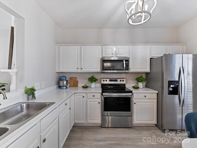 kitchen with white cabinetry, stainless steel appliances, a sink, and light countertops